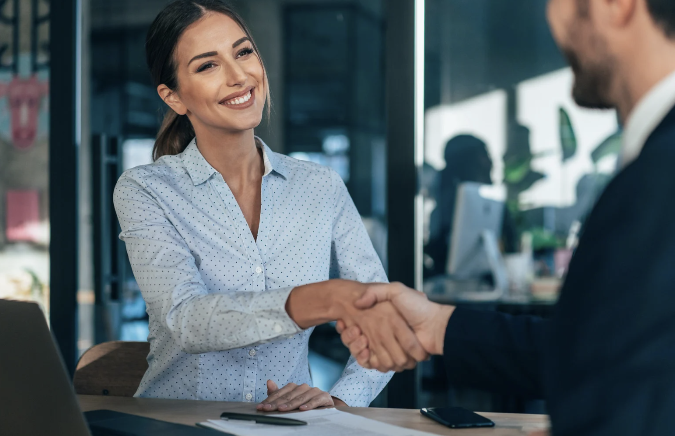 man and woman shaking hands representing the sale of a business